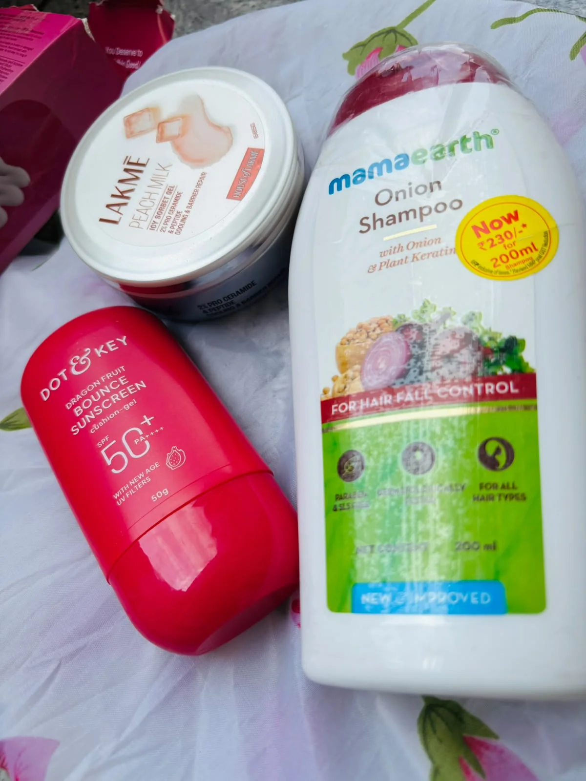 Lakmé Peach Milk, Mamaearth Onion Shampoo and Dot and Key sunscreen arranged on floral fabric